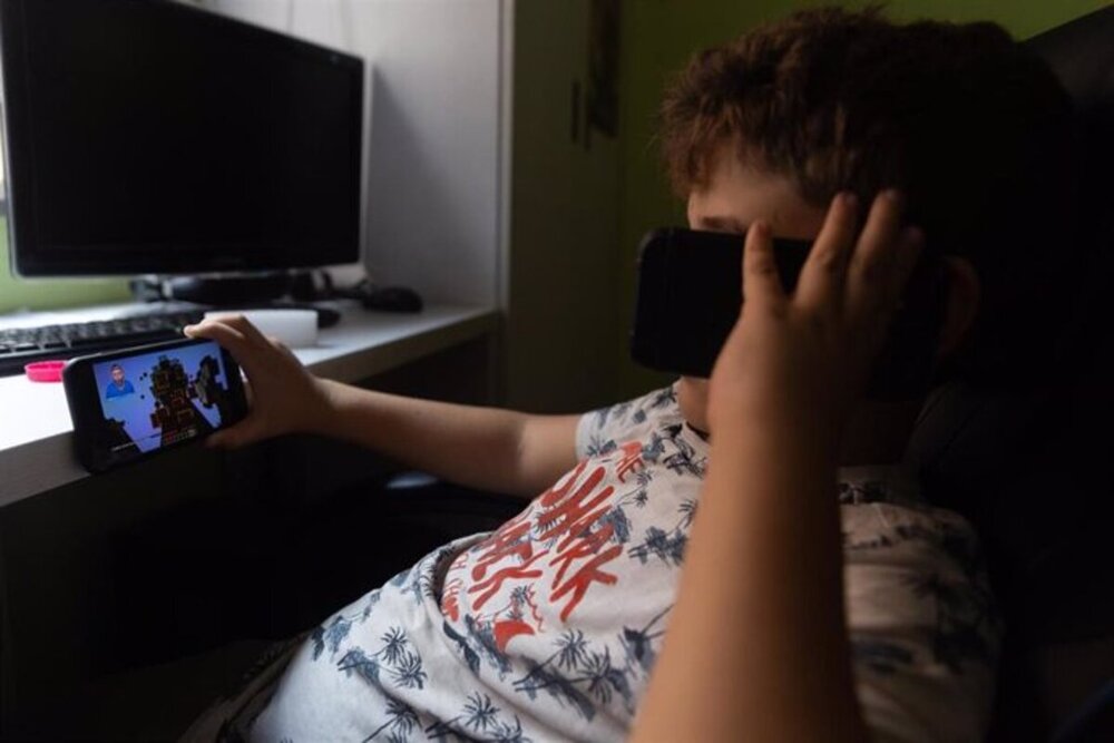 Un niño con dos teléfonos móviles