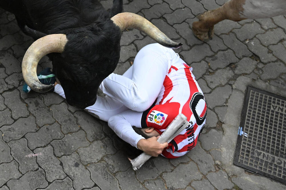 Un mozo se protege al paso de los toros de Victoriano del Río en el tercer encierro de los Sanfermines