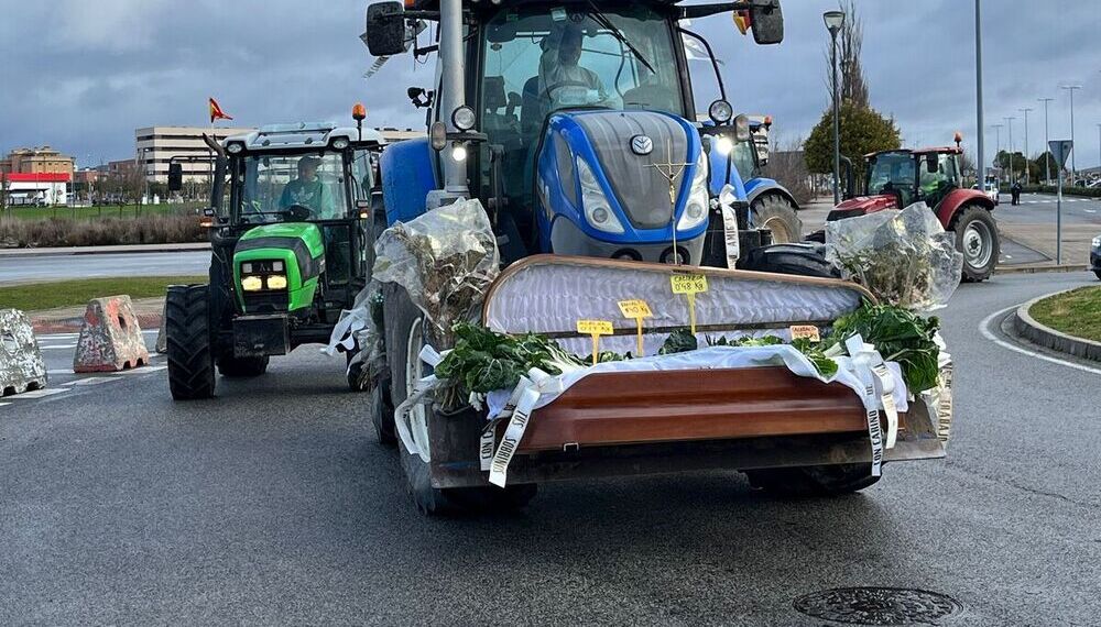 Un tractor lleva un ataúd de verduras para protestar por mantener vivo el campo